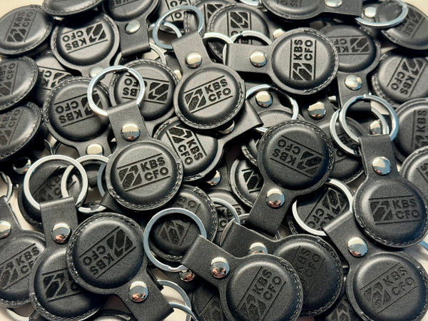 Black leather AirTag holders engraved with a corporate logo, bulk order