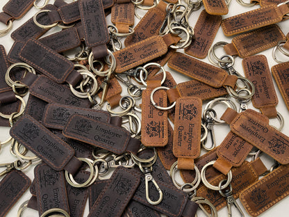 Bulk order of dark brown leather keychains engraved with a company logo